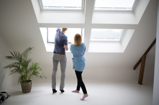Un couple analyse l'isolation des fenêtres de leur maison pour connaitre la performance énergétique (PEB) de leur habitation.